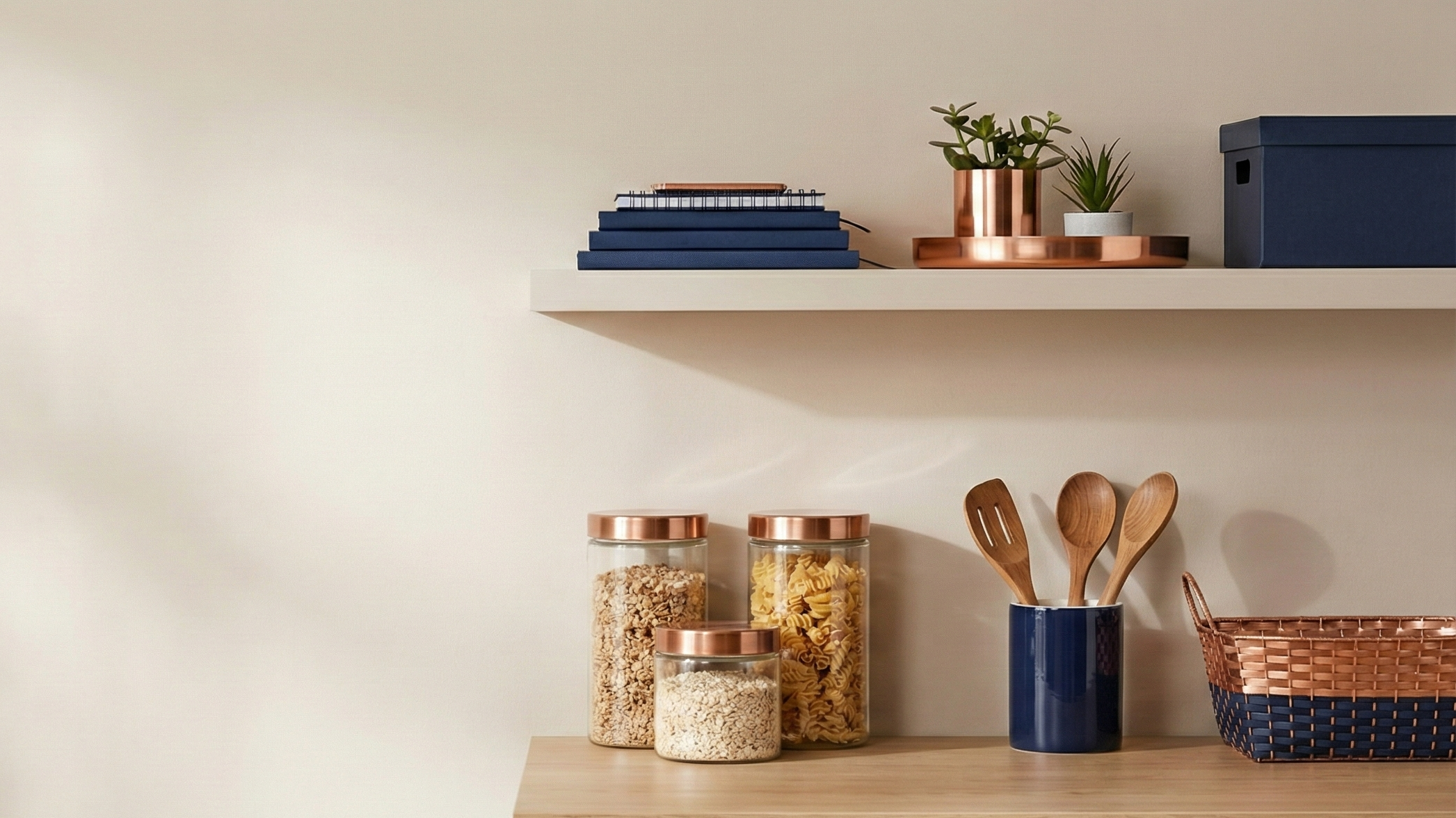 Shelving unit with jars, books, and kitchen utensils against a beige wall.